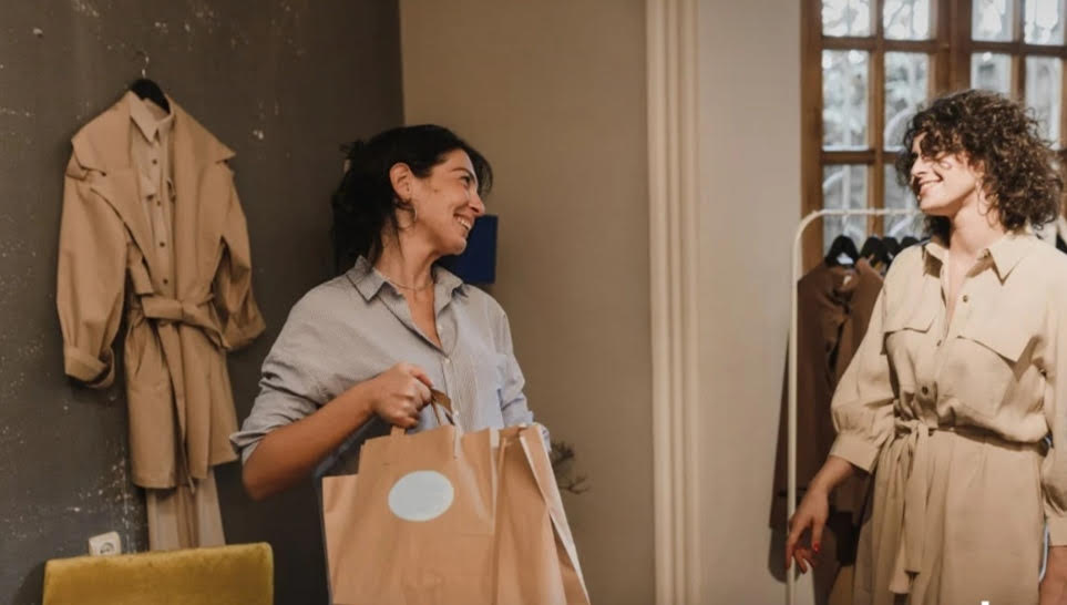 mujer haciendo compras y hablando con vendedora en tienda de ropa